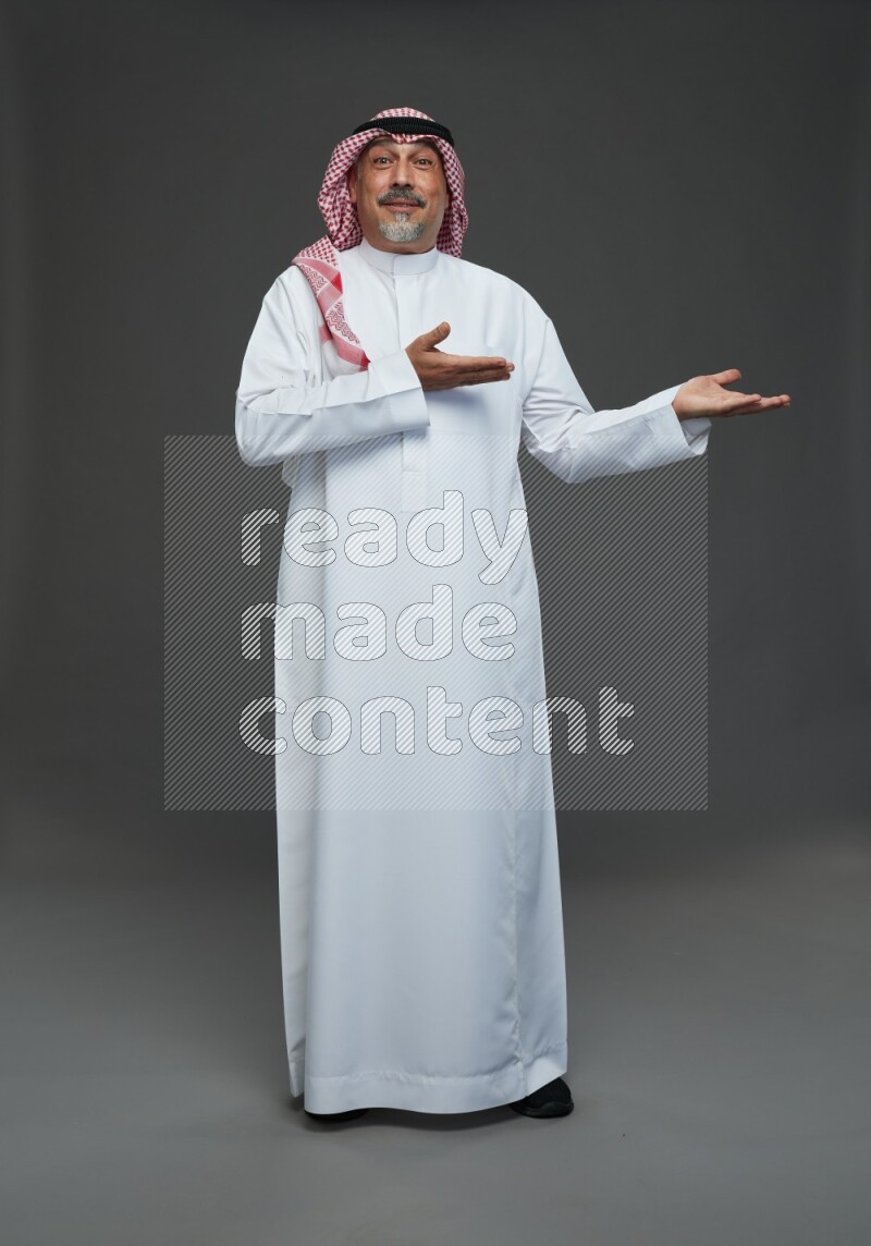 Saudi man with shomag Standing Interacting with the camera on gray background