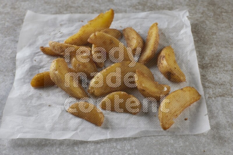 wedges potato on parchment paper on grey textured counter top