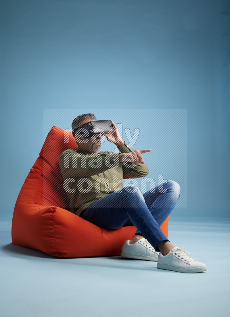 A man sitting on an orange beanbag and gaming with VR