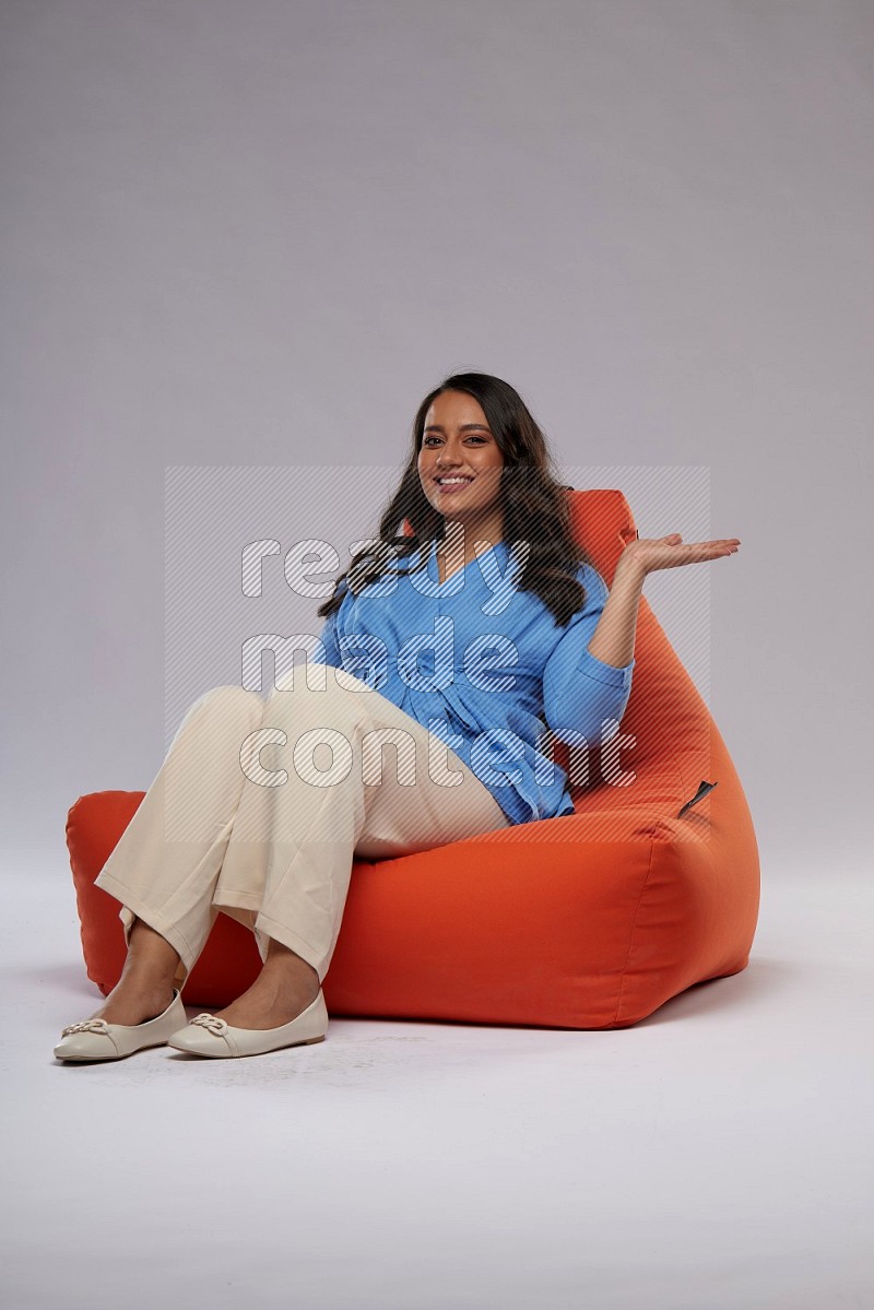 A woman sitting on an orange beanbag and interacting with the camera