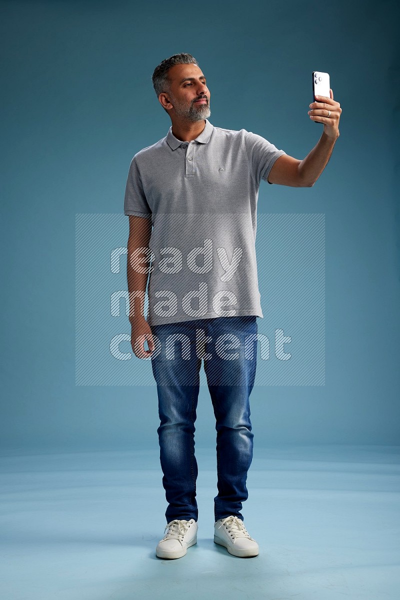 Man Standing taking selfie on blue background