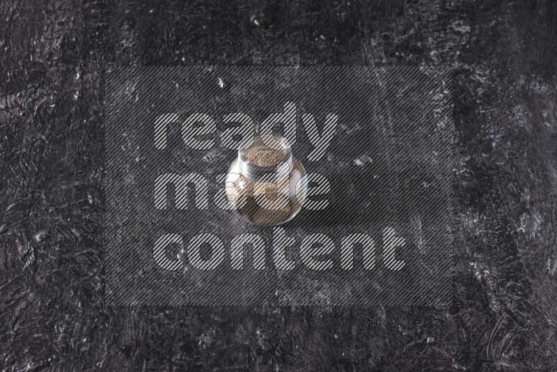 بودرة الفلفل الأسود في وعاء زجاجي علي خلفية سوداء