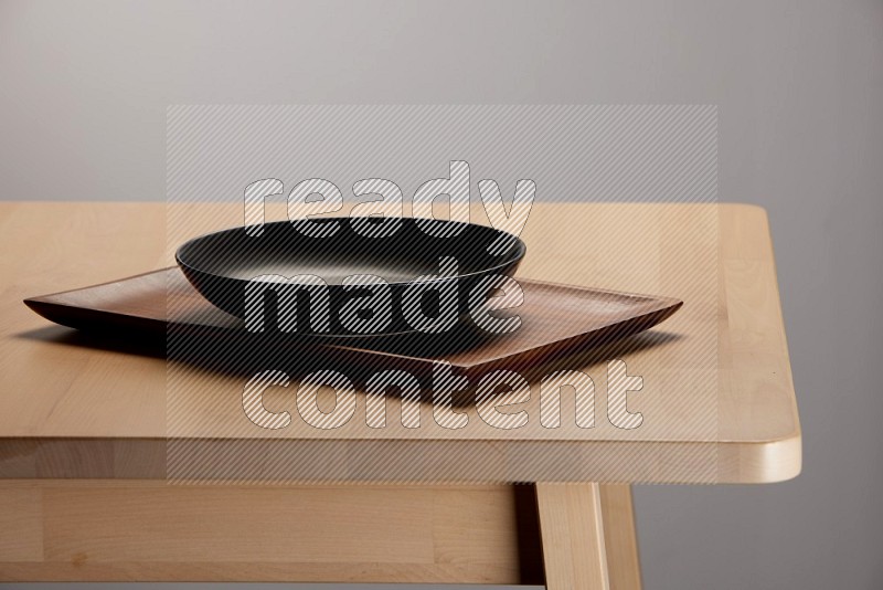 black plate on a rectangular wooden tray on the edge of wooden table