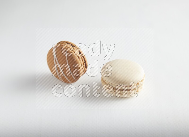 45º Shot of of two assorted Brown Irish Cream, and White Caramel fleur de sel macarons on white background