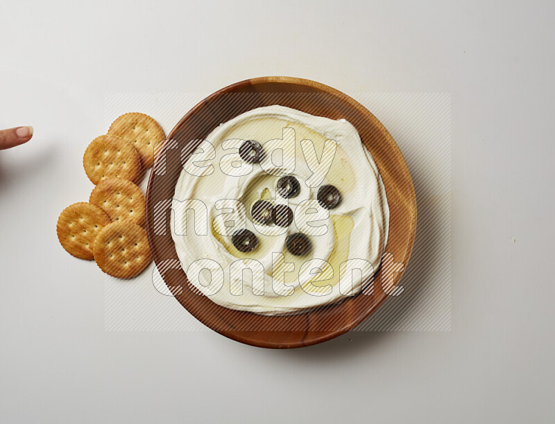 Lebnah garnished with sliced olives in a wooden plate on a white background