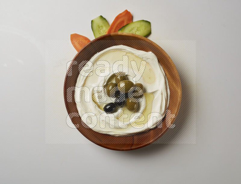 Lebnah garnished with whole olives in a wooden plate on a white background
