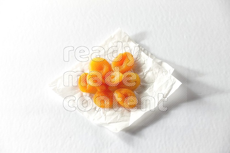 Dried apricots on a crumpled piece of paper on a white background in different angles