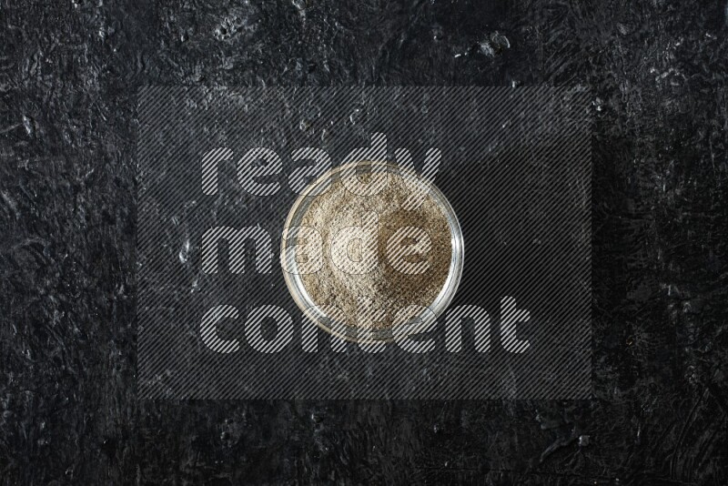 وعاء زجاجي ممتلئ ببودرة الهيل علي خلفية سوداء