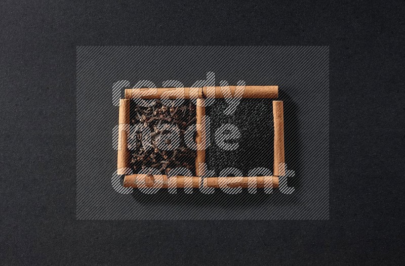 2 squares of cinnamon sticks full of black seeds and cloves on black flooring