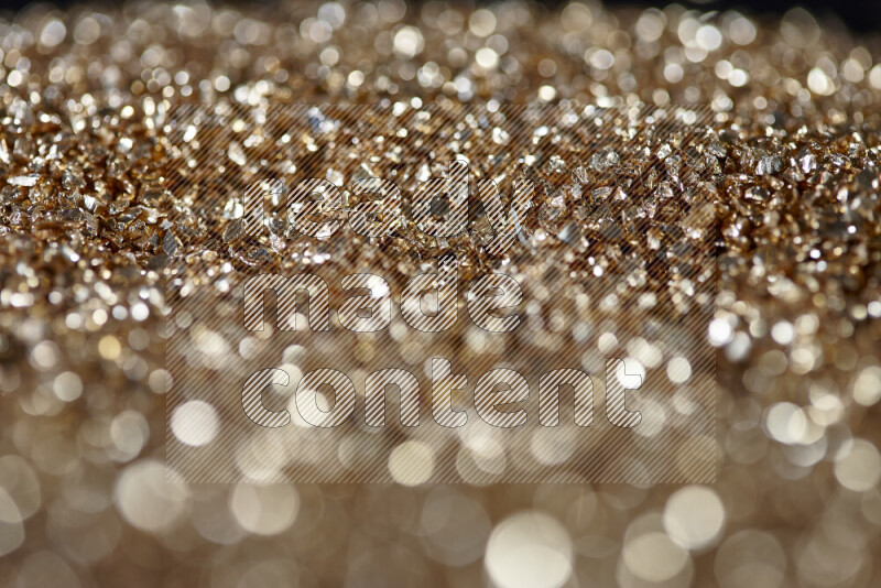 Gold shimmering fragments of glass scattered on a black background