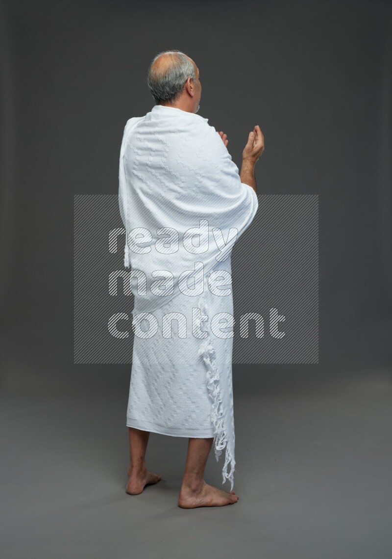 A man wearing Ehram Standing dua'a on gray background