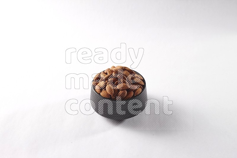 Almonds in a black pottery bowl on white background