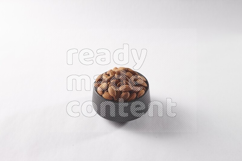 Almonds in a black pottery bowl on white background