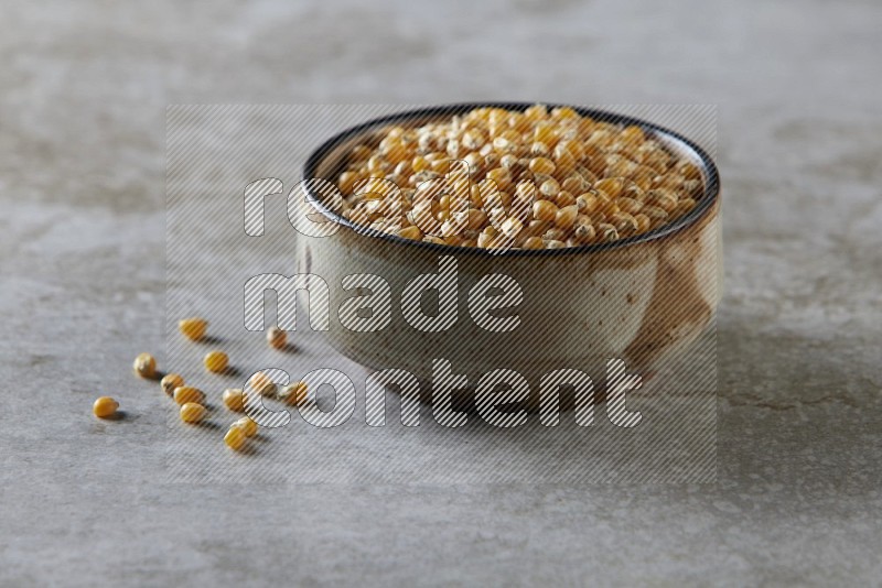 corn kernel in multi-colored pottery bowl on a grey textured countertop