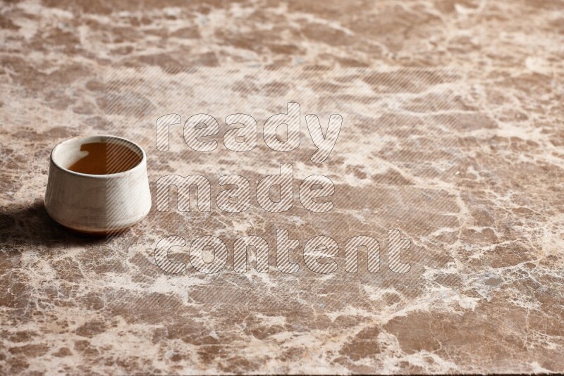 A beige pottery bowl on beige marble background
