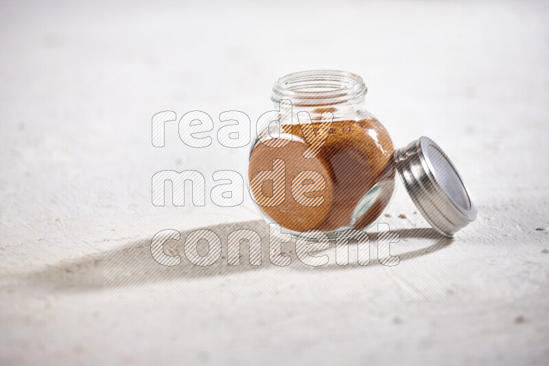 A glass jar full of ground paprika powder on white background