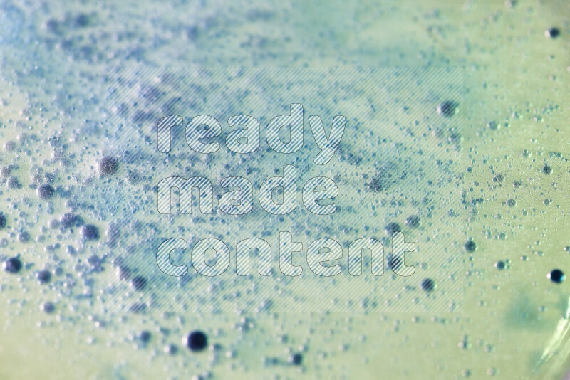 Close-ups of abstract blue watercolor drops on oil Surface on green background