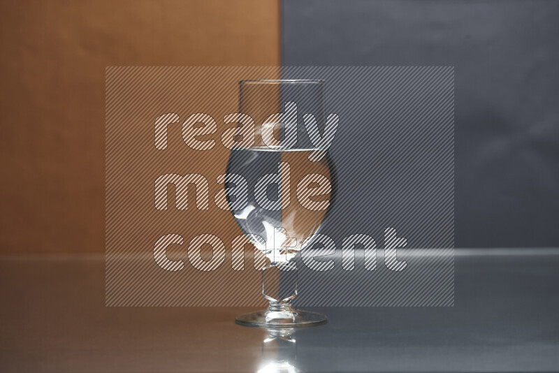 The image features a clear glassware filled with water, set against brown and dark blue background