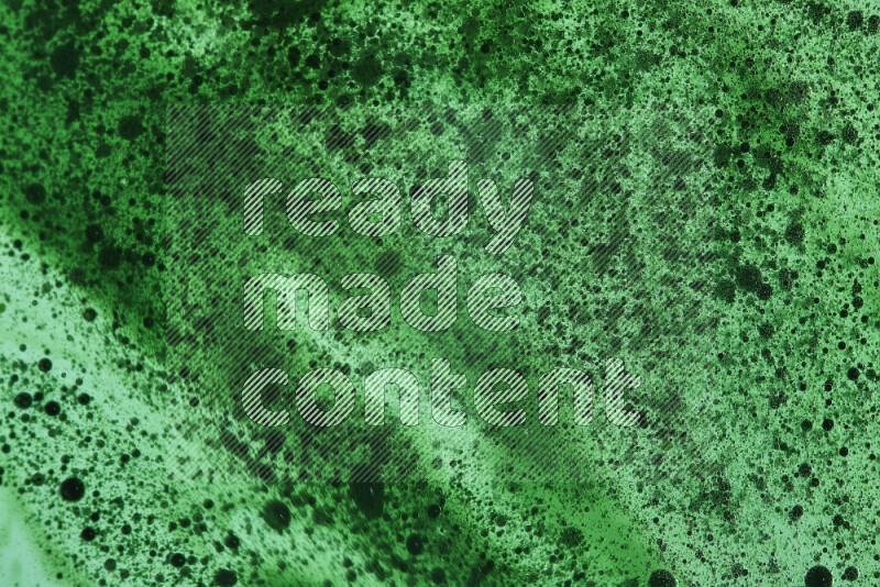 Close-ups of abstract green watercolor drops on oil Surface on green background