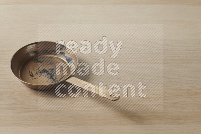 A small copper pan on light wooden background