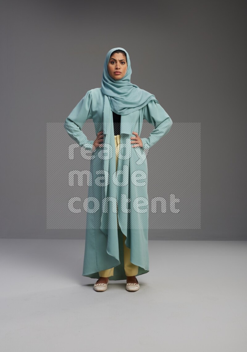 Saudi Woman wearing Abaya standing interacting with the camera on Gray background