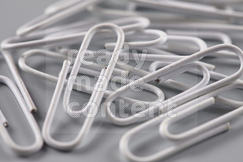 White paper clips isolated on a grey background