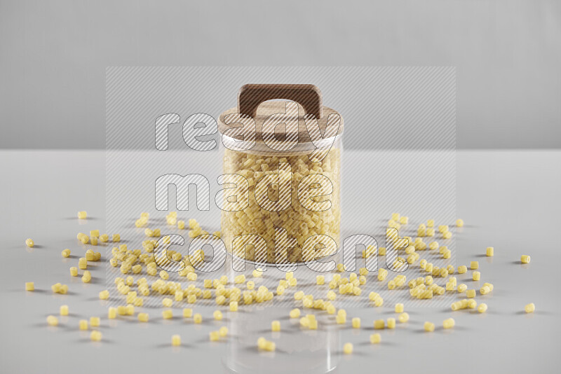 Raw pasta in a glass jar on light grey background