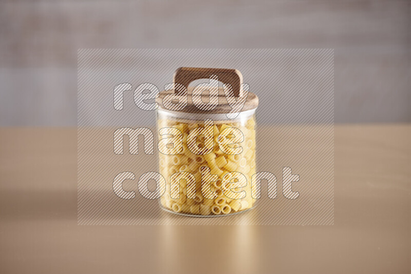 Raw pasta in glass jars on beige background