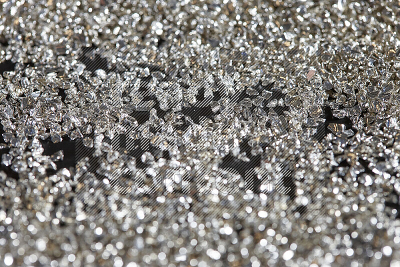 Silver shimmering fragments of glass scattered on a black background