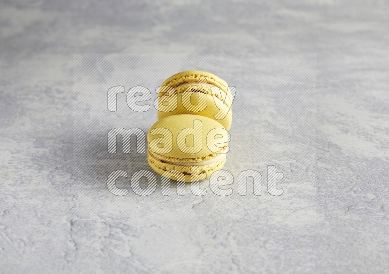 45º Shot of two Yellow Lime macarons  on white  marble background