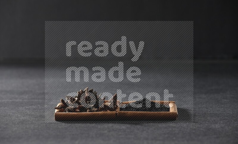 2 squares of cinnamon sticks full of black seeds and star anise on black flooring