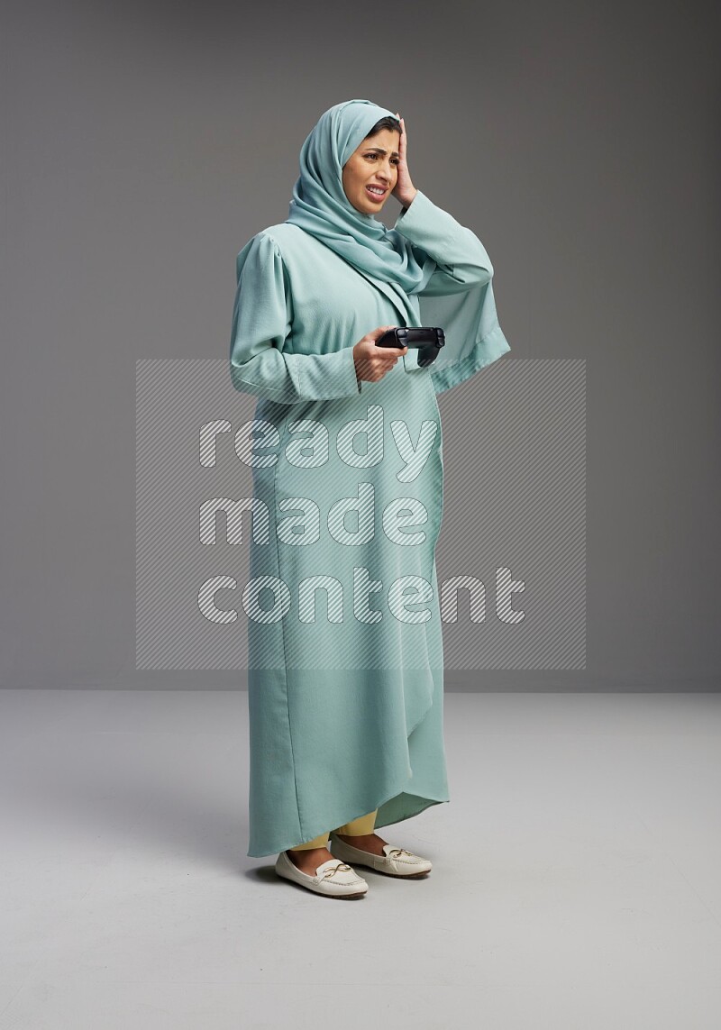 Saudi Woman wearing Abaya standing Playing Games on Gray background
