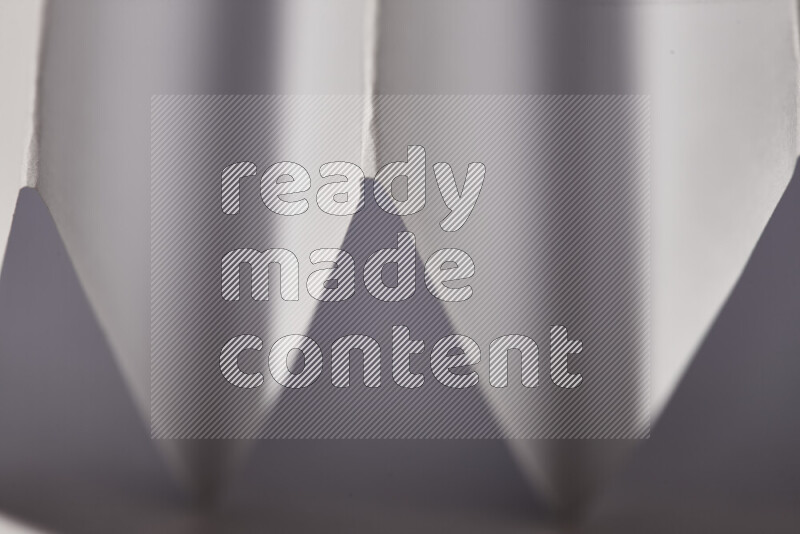A close-up abstract image showing sharp geometric paper folds in grey gradients