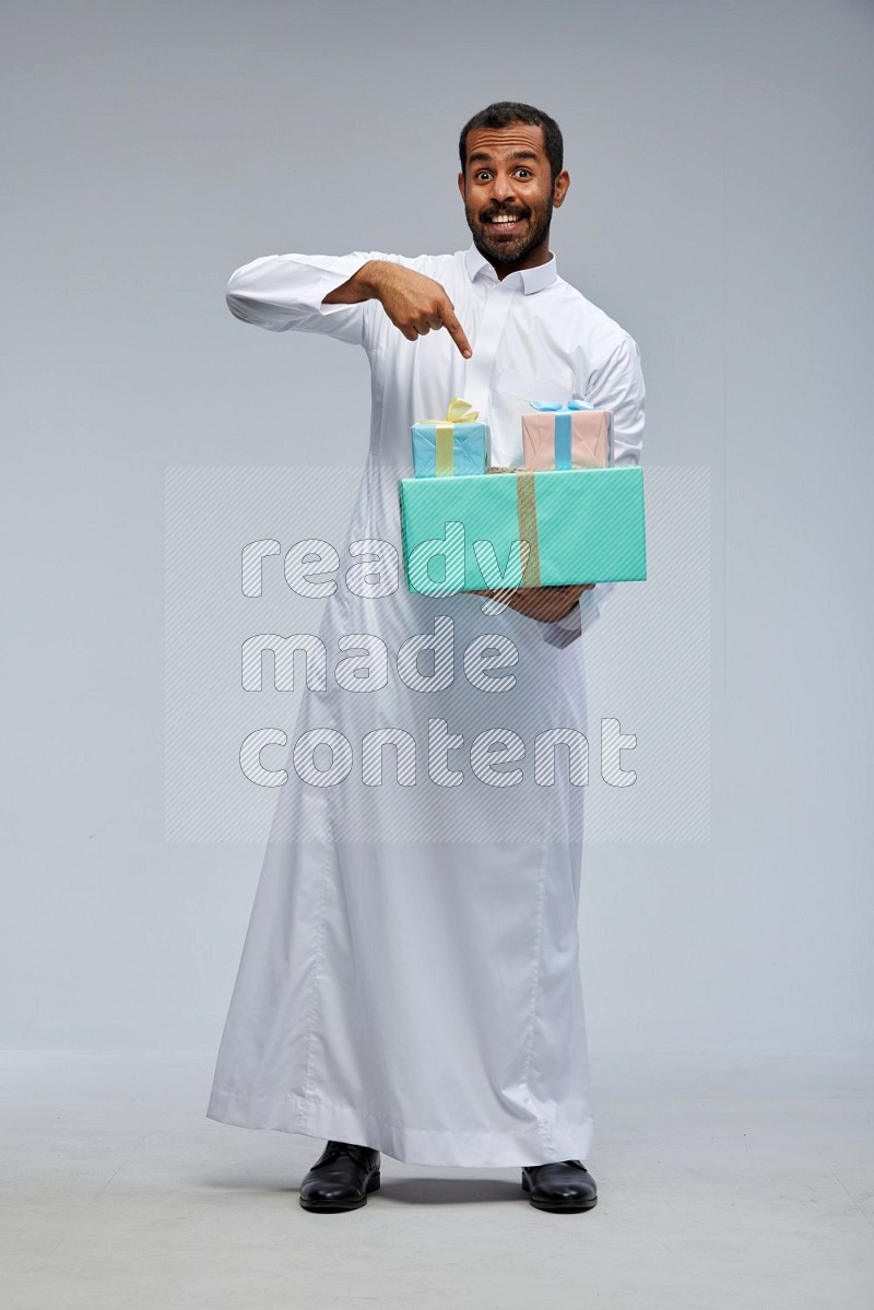 Saudi man Wearing thob standing holding gift box on Gray background