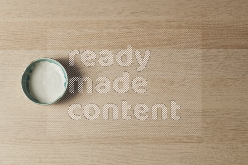 A multicolored pottery bowl on light wooden background