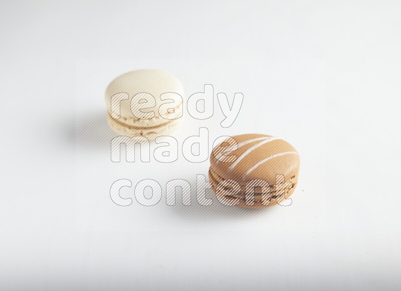 45º Shot of of two assorted Brown Irish Cream, and White Caramel fleur de sel macarons on white background