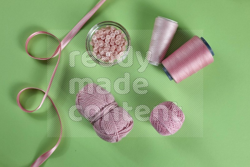 Pink sewing supplies on green background