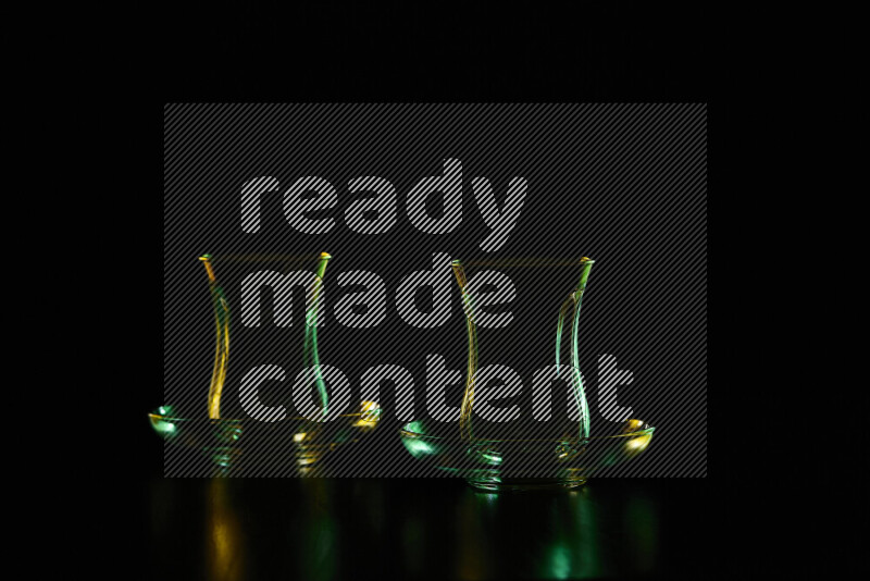 Glassware with rim light in green and yellow against black background