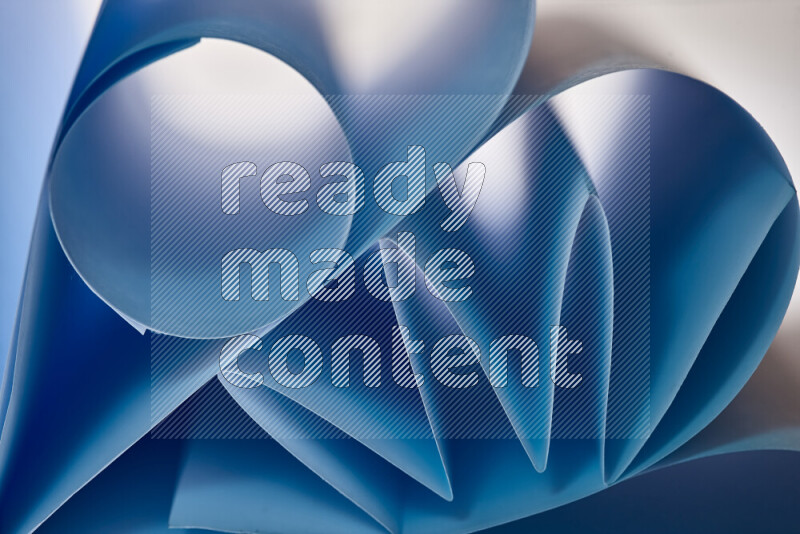 An artistic display of paper folds creating a harmonious blend of geometric shapes, highlighted by soft lighting in blue tones