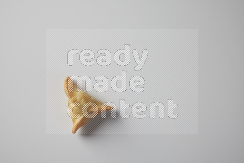 One fried sambosa from a top angle on a white background