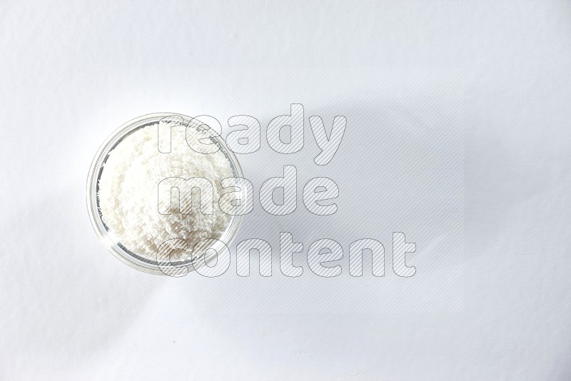 A glass bowl full of desiccated coconut on a white background in different angles