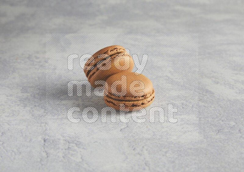 45º Shot of two Brown Coffee macarons  on white  marble background
