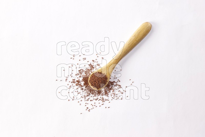 A wooden spoon full of garden cress seeds on a white flooring