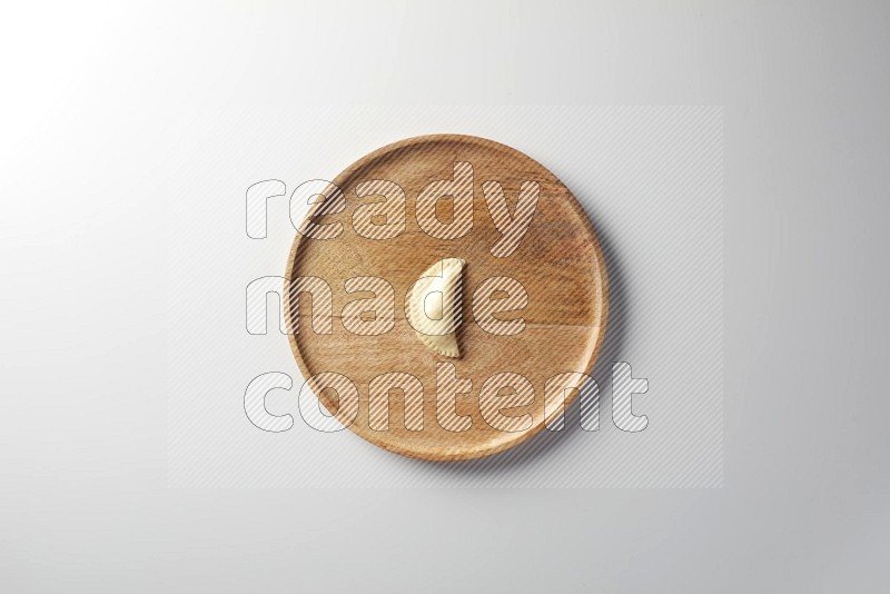 A single Sambosa on a wooden round plate on a white background