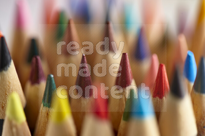 تلتقط الصورة صورة مقربة لأقلام خشبية ملونة حادة على خلفية متعددة الألوان