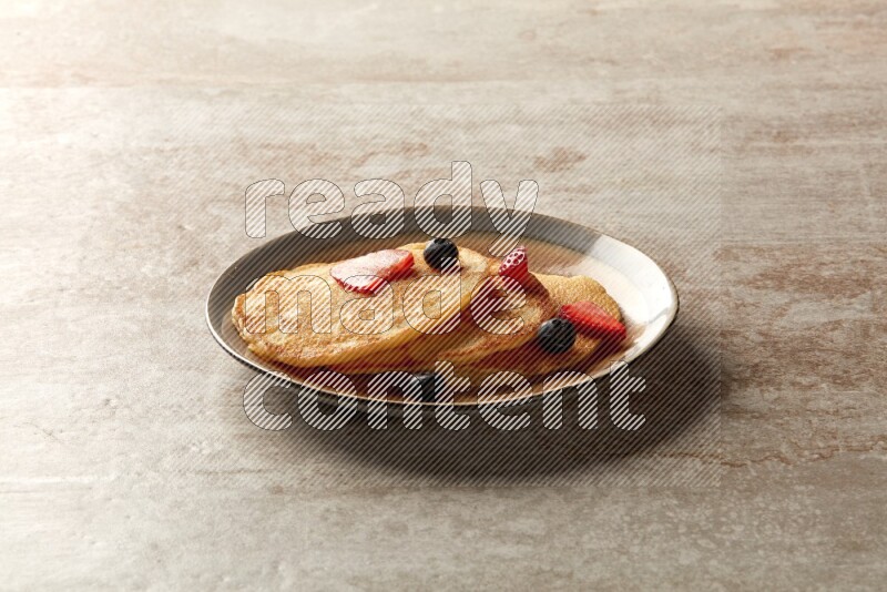 Three stacked mixed berries pancakes in a bicolor plate on beige background