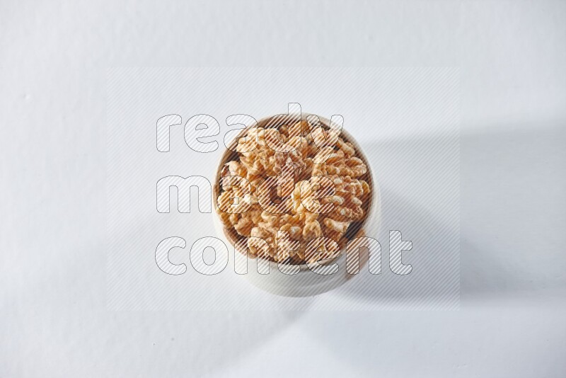 A beige ceramic bowl full of peeled walnuts on a white background in different angles