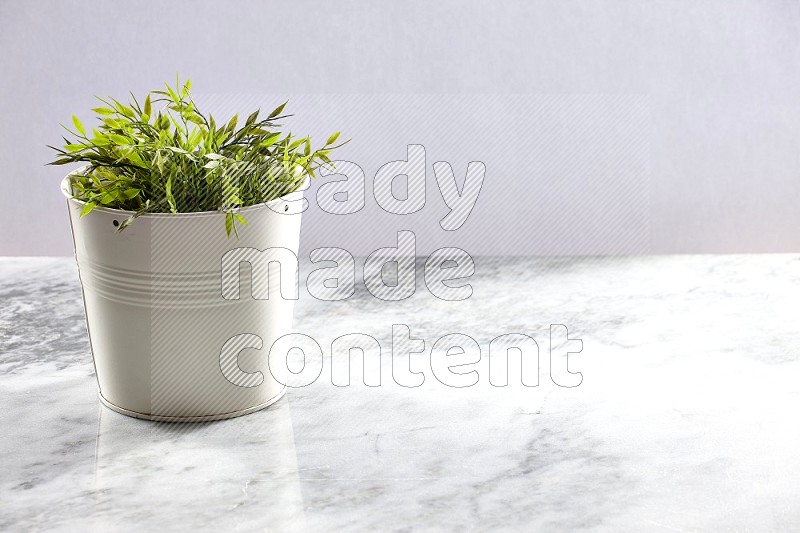 Artificial Plant in White pot on Light Grey Marble Background 45 degree angle