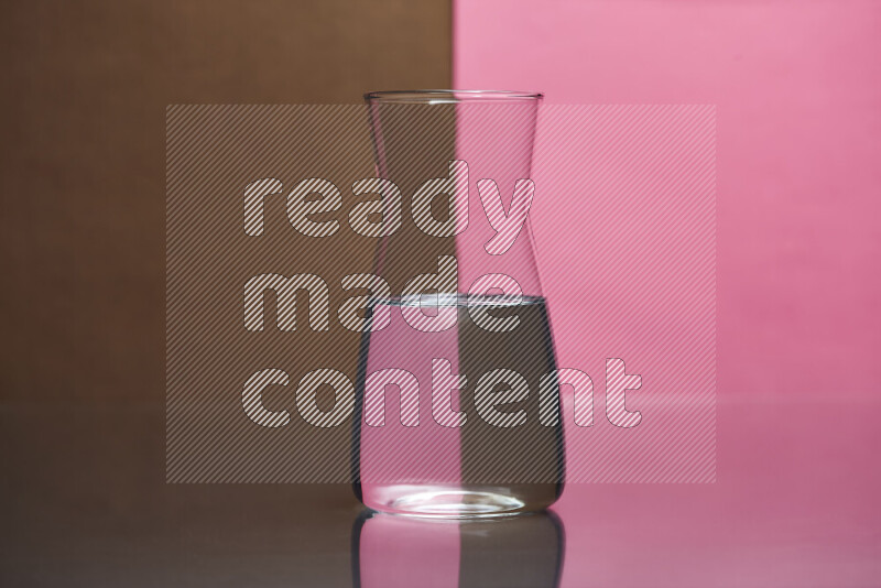 The image features a clear glassware filled with water, set against brown and pink background