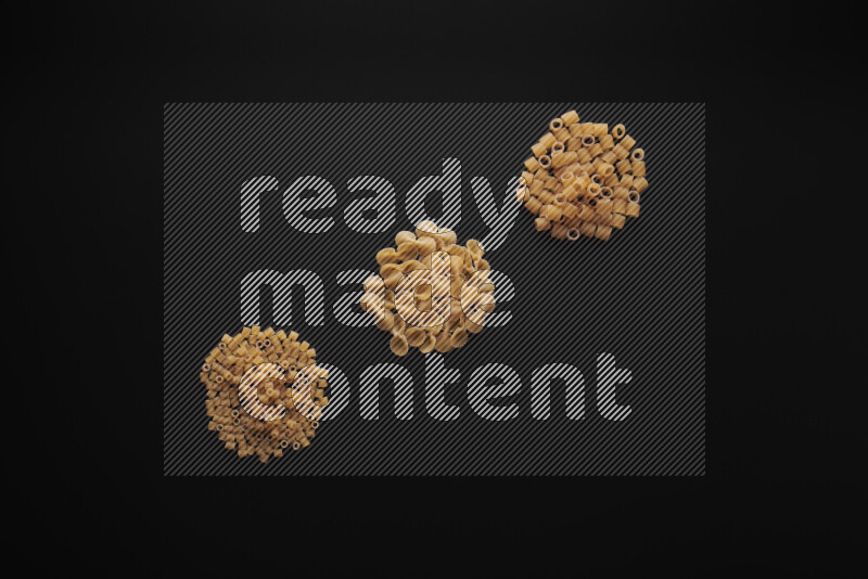 Different pasta types in bunches on black background
